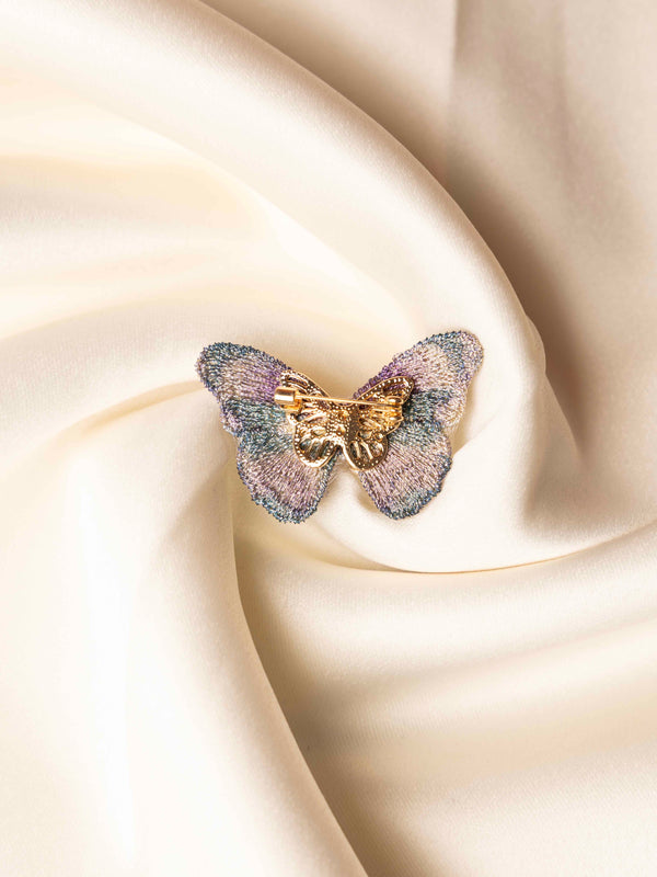Butterfly-shaped jewelry on a soft beige fabric background