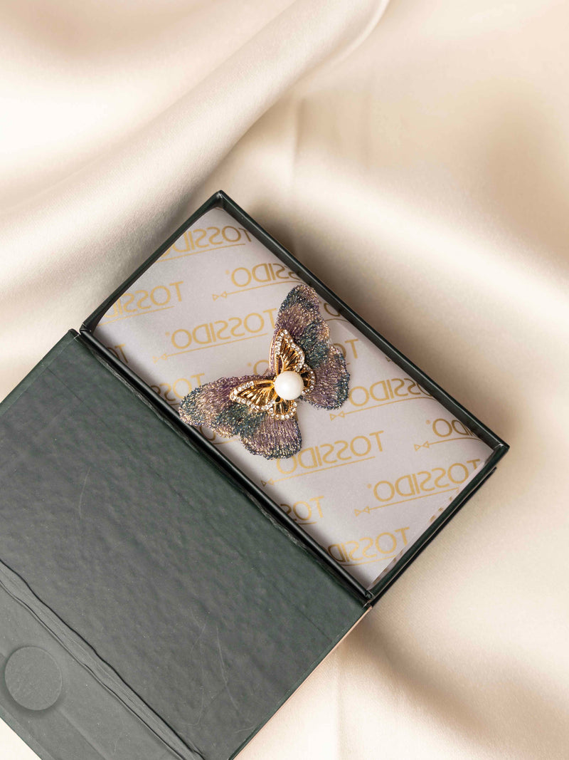 Butterfly-shaped brooch in a branded box on a light background
